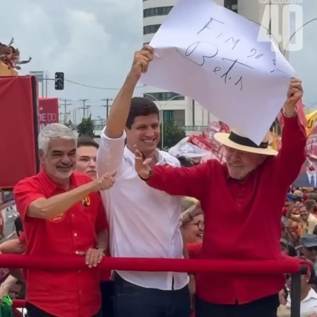 Constrangido, João Campos segura cartaz contra bets escrito por Lula
